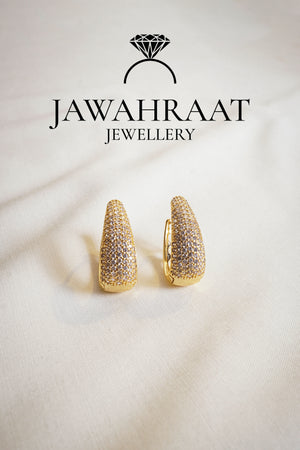 Close-up of gold-tone huggie earrings with clear pave stones from Jawahraat Jewellery