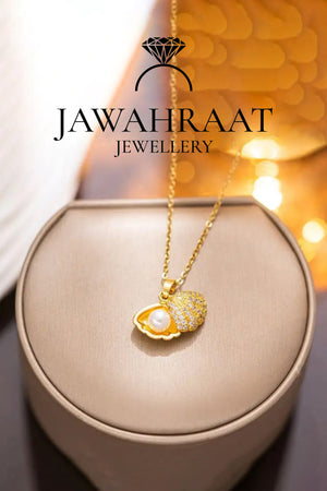 Golden seashell pearl necklace laid flat on a surface, highlighting both the open shell with faux pearl and the detailed second shell charm on a delicate gold-toned chain.