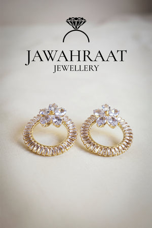 Front view of gold-tone hoop earrings by Jawahraat Jewellery, featuring clear cubic zirconia and golden baguette-cut crystals in an elegant circular design.
