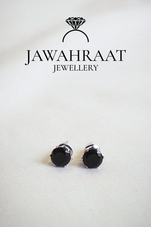 Close-up of matching black teardrop stud earrings by Jawahraat Jewellery, featuring silver-toned edges and shimmering crystal details for a refined, elegant finish.