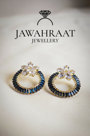 Front view of navy blue hoop earrings by Jawahraat Jewellery, designed with sparkling clear zirconia and deep blue baguette-cut crystals on a golden hoop base.