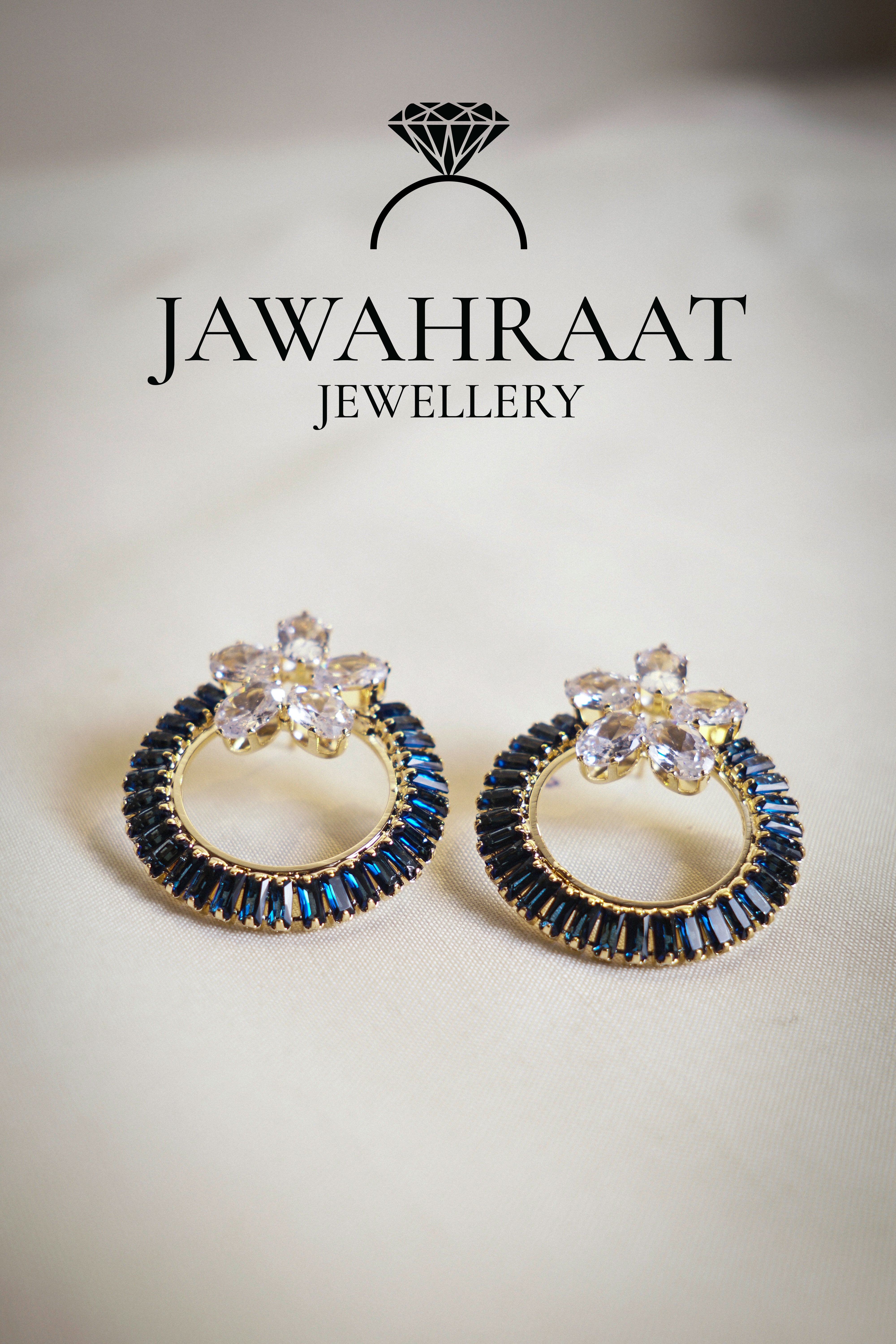 Front view of navy blue hoop earrings by Jawahraat Jewellery, designed with sparkling clear zirconia and deep blue baguette-cut crystals on a golden hoop base.