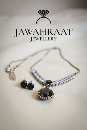 Elegant silver-toned necklace and earring set by Jawahraat Jewellery, featuring a black teardrop pendant and matching stud earrings, both adorned with sparkling crystal accents.