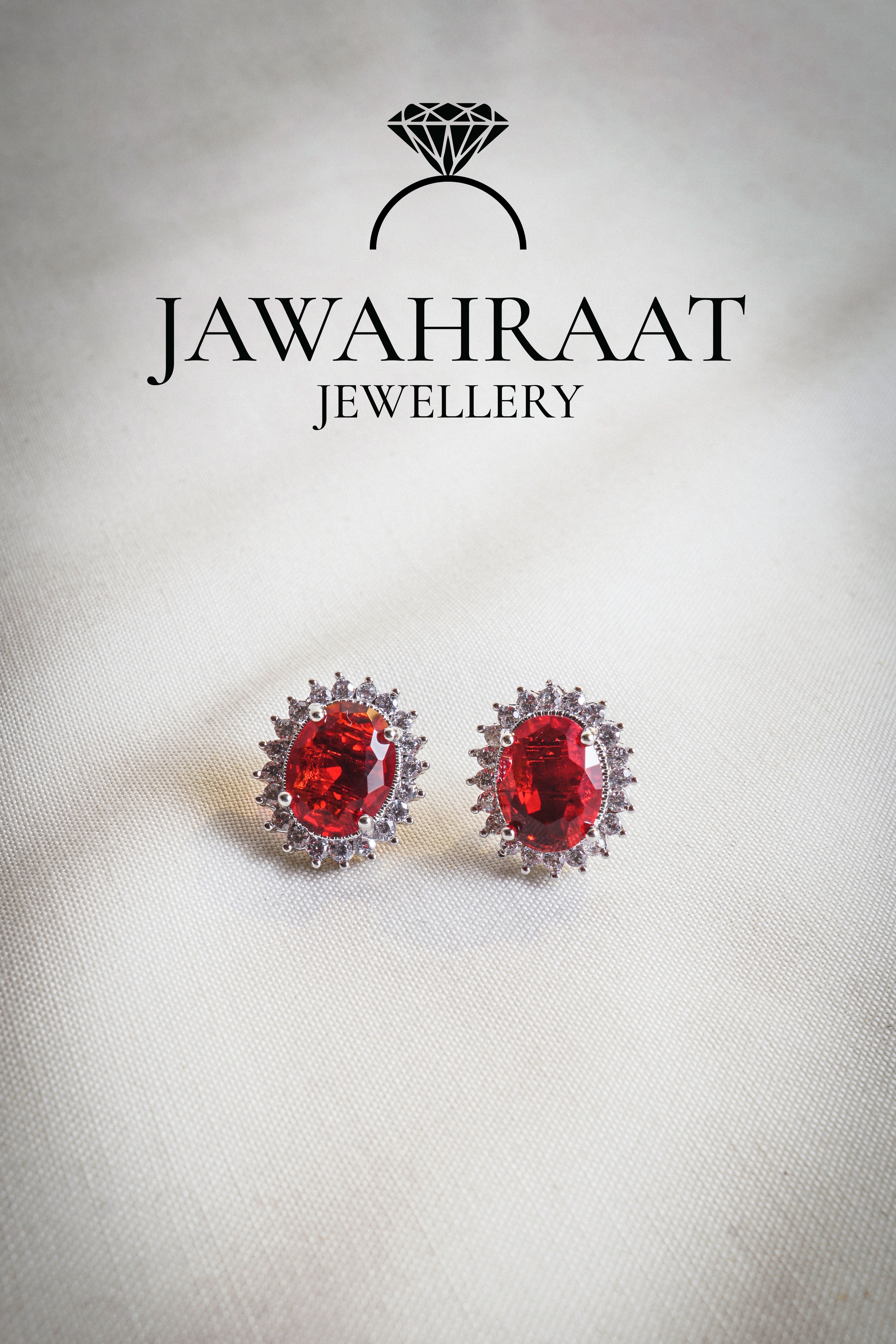 Close-up of matching silver earrings with red oval gemstones and sparkling white accents from the Red Oval Gem Set.