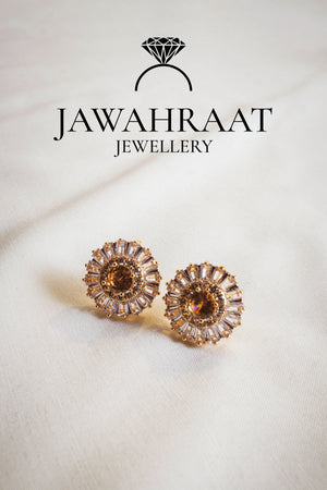 Close-up of gold-plated teardrop earrings with peach-colored stones, ideal for weddings and festive looks