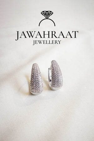 Silver-tone crystal huggie earrings featuring pavé detailing from Jawahraat Jewellery