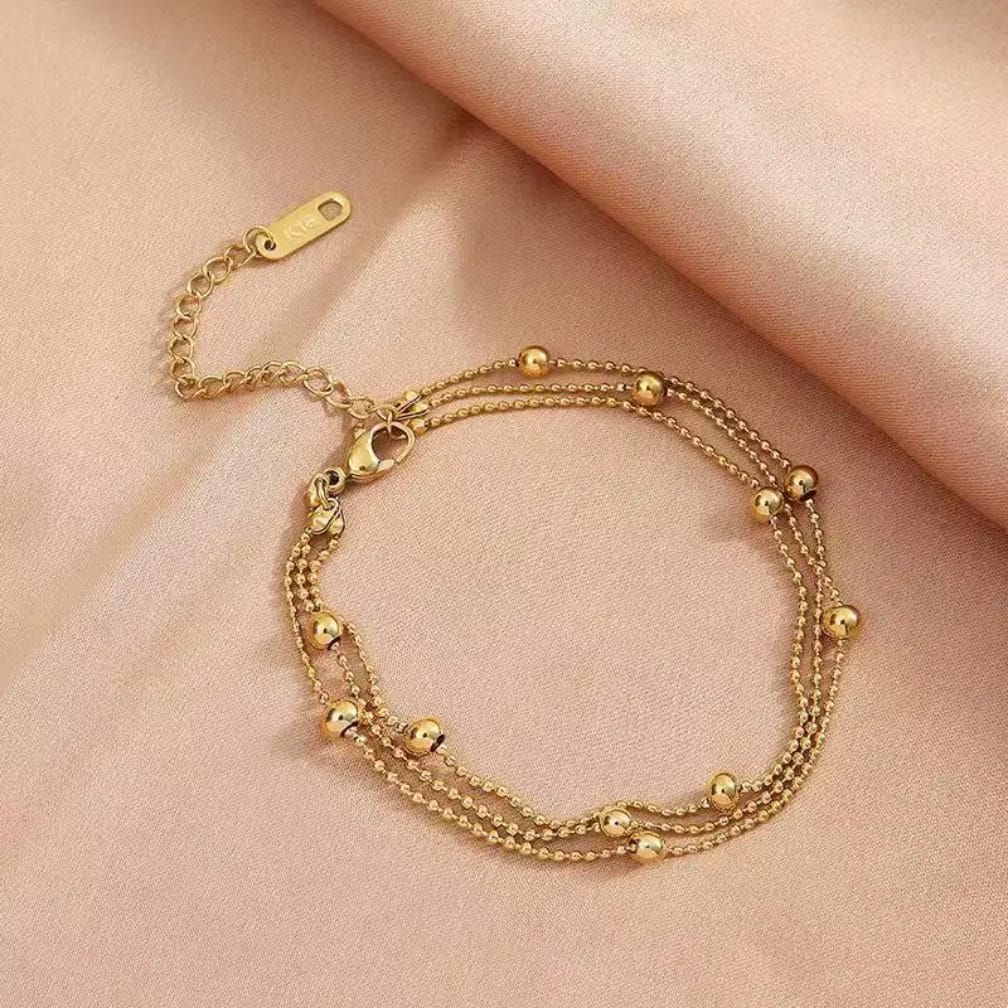 Elegant triple layer gold bead bracelet on soft background
