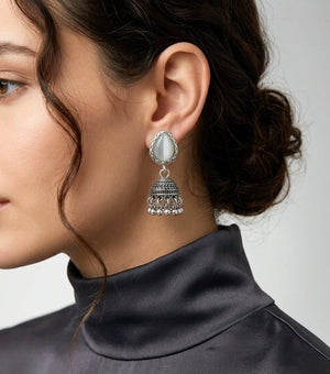 Woman wearing silver oxidized jhumka drop earrings with stone detail