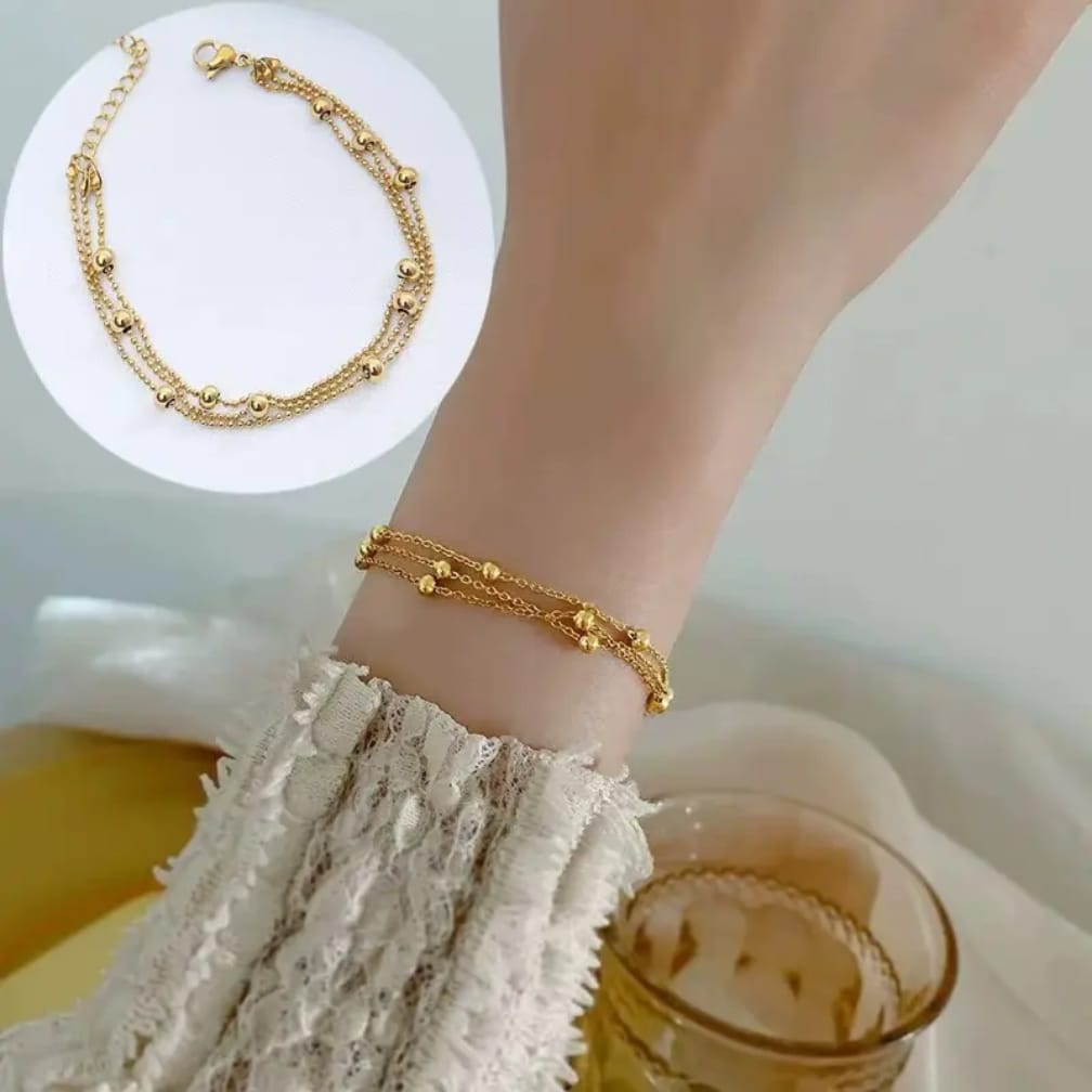 Triple layer gold bead bracelet worn on wrist