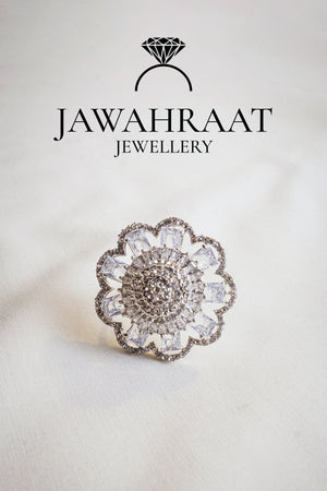 Front view of a silver-tone floral cocktail ring by Jawahraat Jewellery, featuring clear baguette and pave crystals in an intricate floral design.

