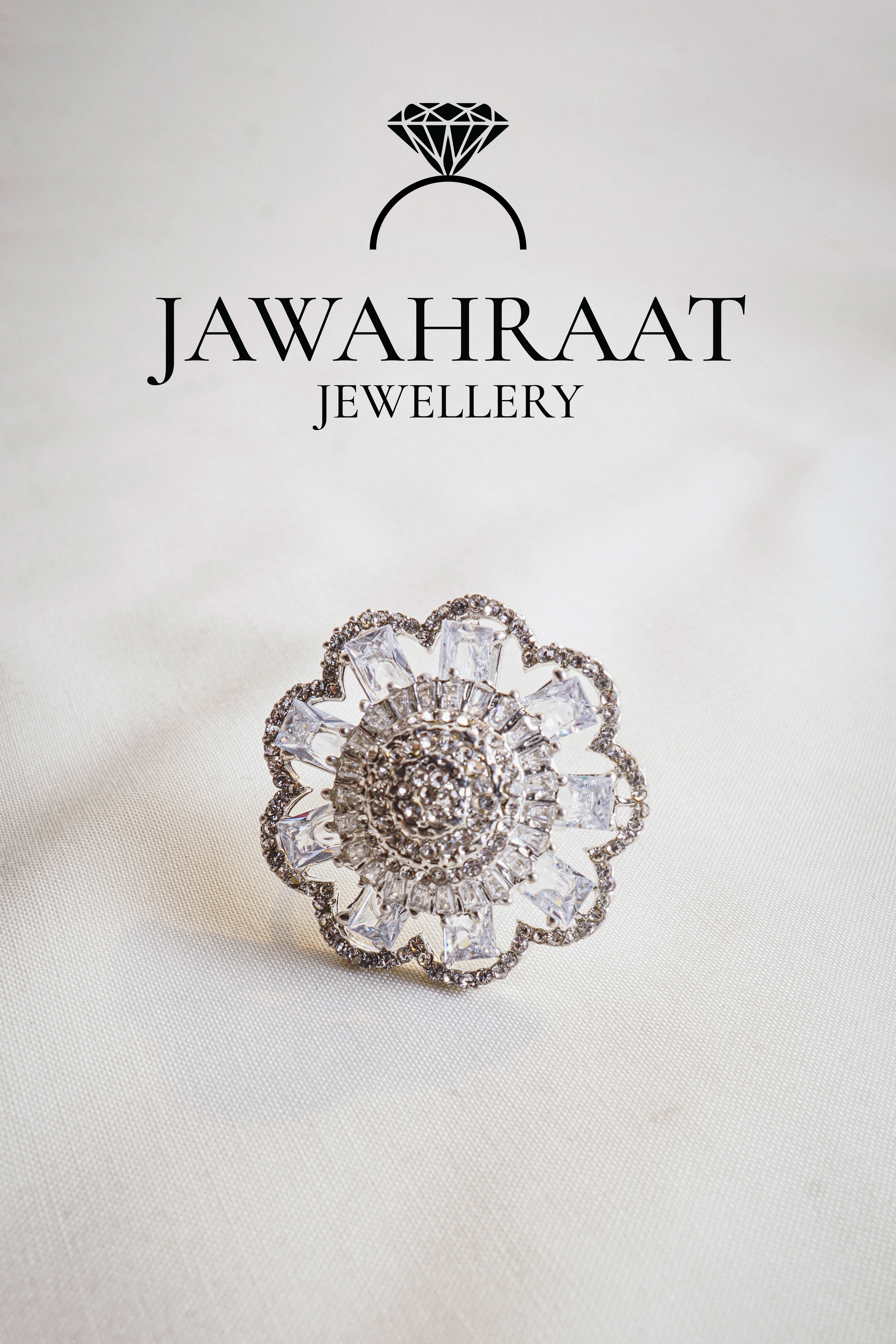 Front view of a silver-tone floral cocktail ring by Jawahraat Jewellery, featuring clear baguette and pave crystals in an intricate floral design.

