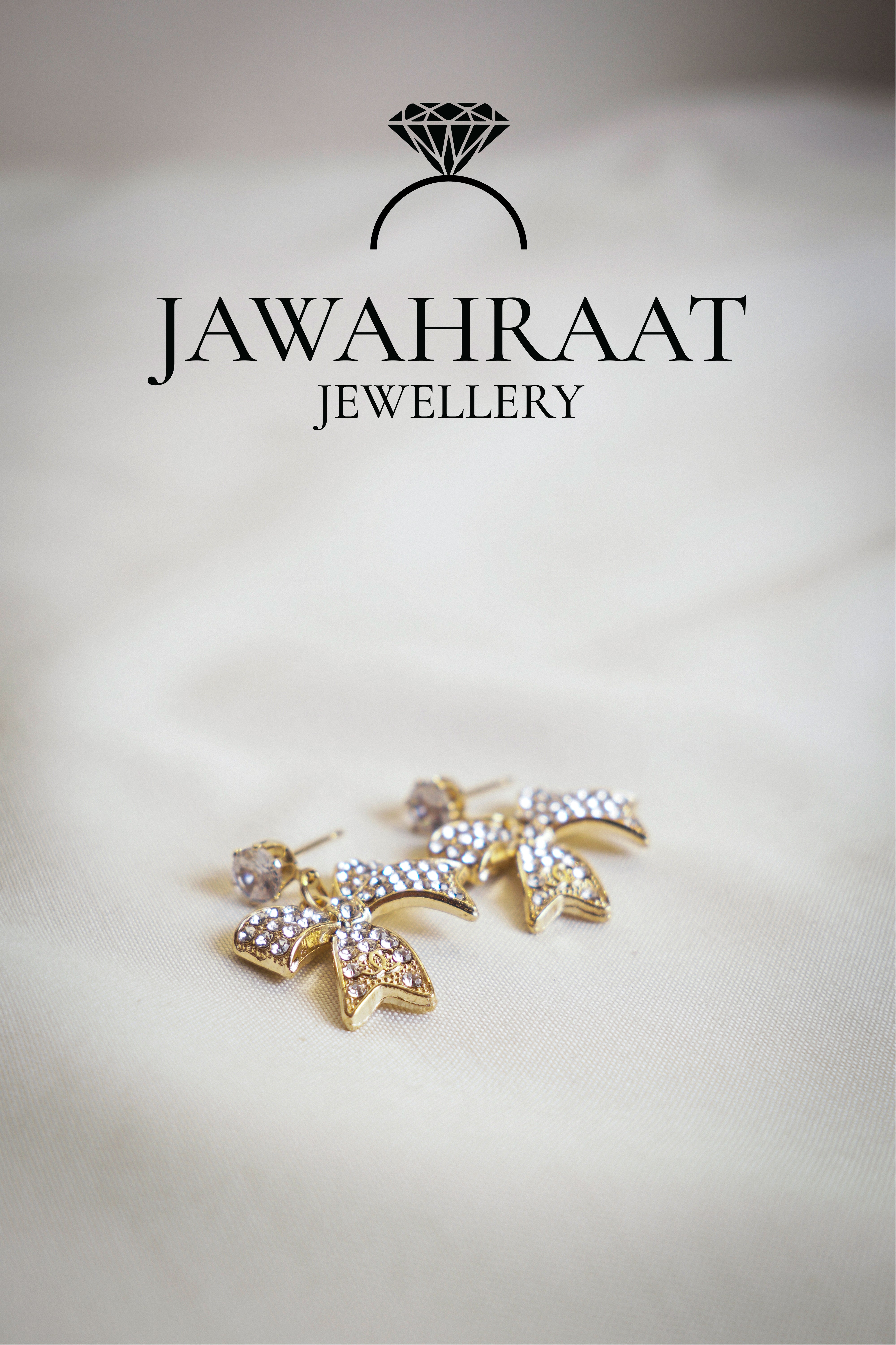 Front view of gold-tone bow dangle earrings by Jawahraat Jewellery, featuring sparkling rhinestone details and a dangling round crystal for added charm.

