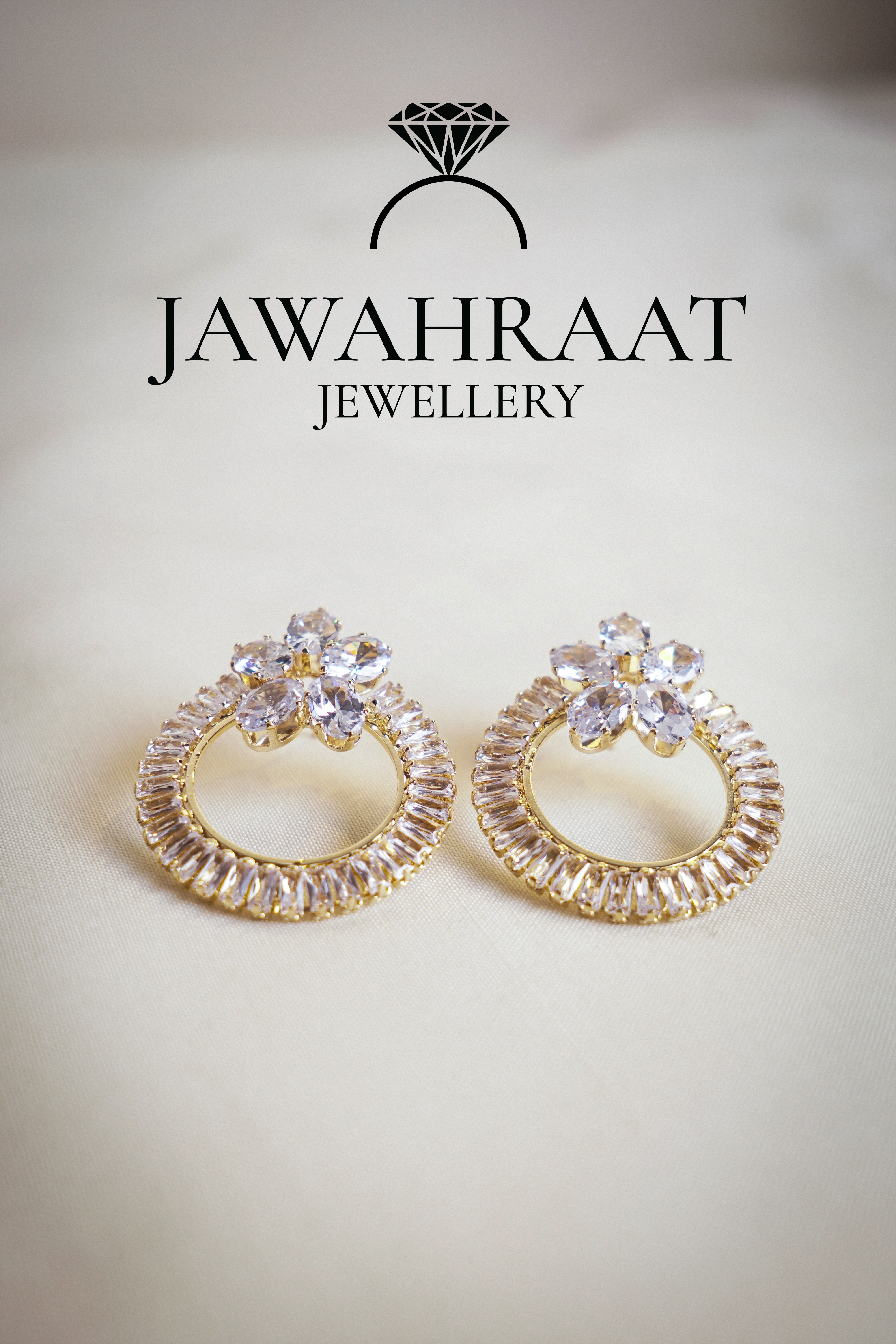 Front view of gold-tone hoop earrings by Jawahraat Jewellery, featuring clear cubic zirconia and golden baguette-cut crystals in an elegant circular design.

