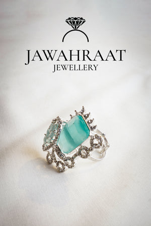 Side view of the Elara ring in aqua teal by Jawahraat Jewellery – silver-tone adjustable ring with rectangular crystal, pavé stones, and scrollwork detailing.


