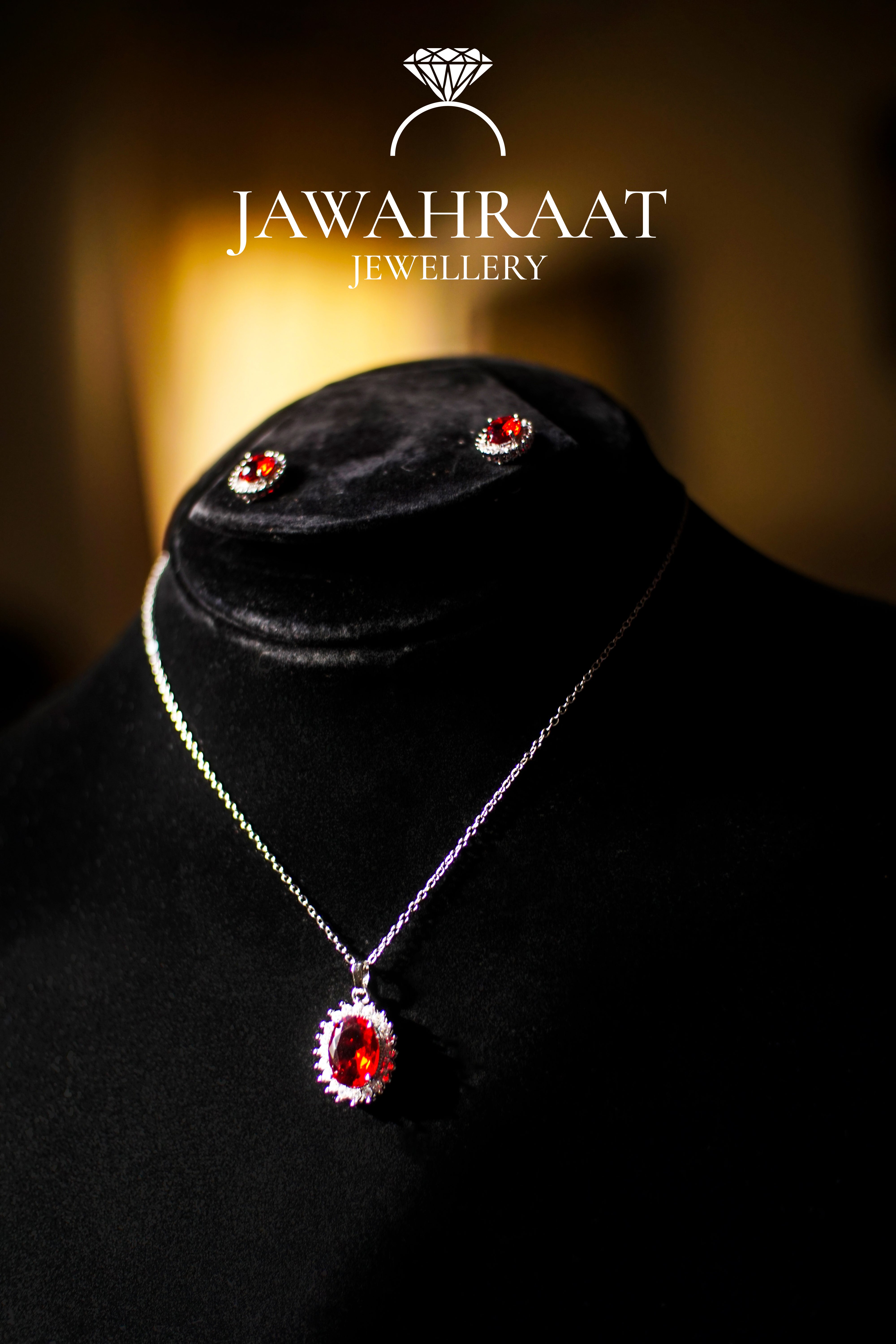 Elegant Red Oval Gem Jewelry Set featuring a silver-toned pendant necklace and matching earrings with red center stones and white accents.

