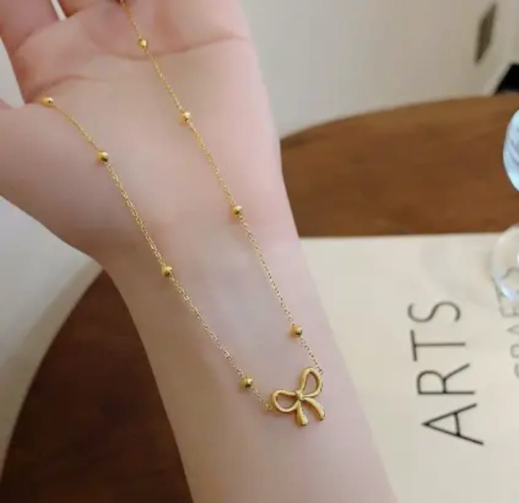 Dainty gold bow necklace showing beaded chain detail
