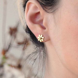 Daisy flower gold stud earrings worn on ear – minimal floral earrings