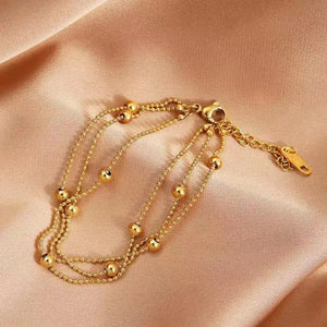 Close-up of gold bead and chain detail on layered bracelet