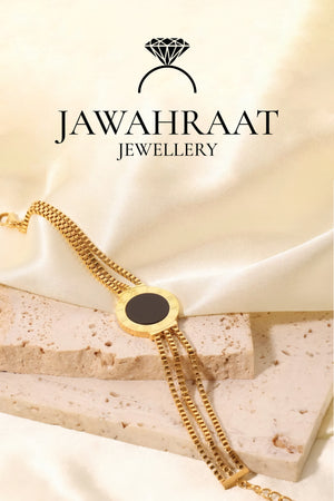 Gold-tone stainless steel artificial bracelet with black onyx circle charm on marble background
