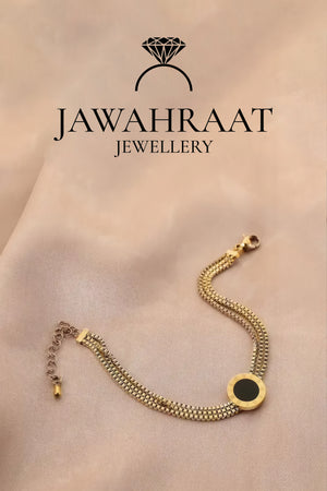 Luxurious gold-tone multi-chain bracelet with black onyx circle pendant draped on silk fabric