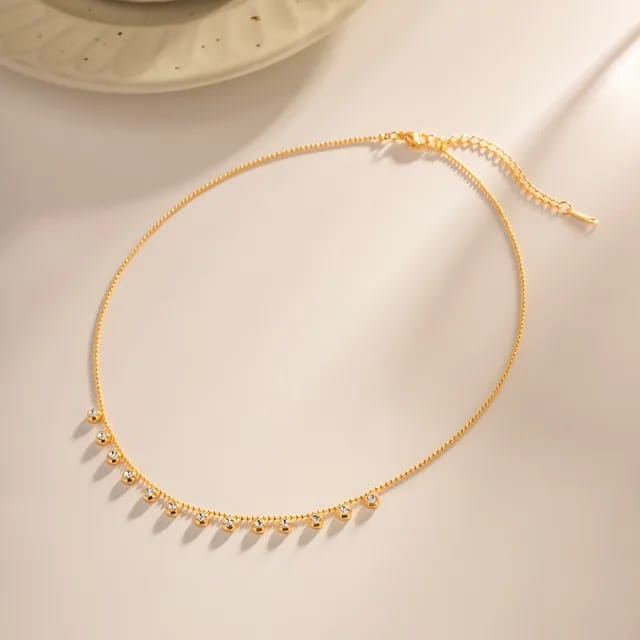 Full view of gold crystal dangle necklace with adjustable chain and clasp