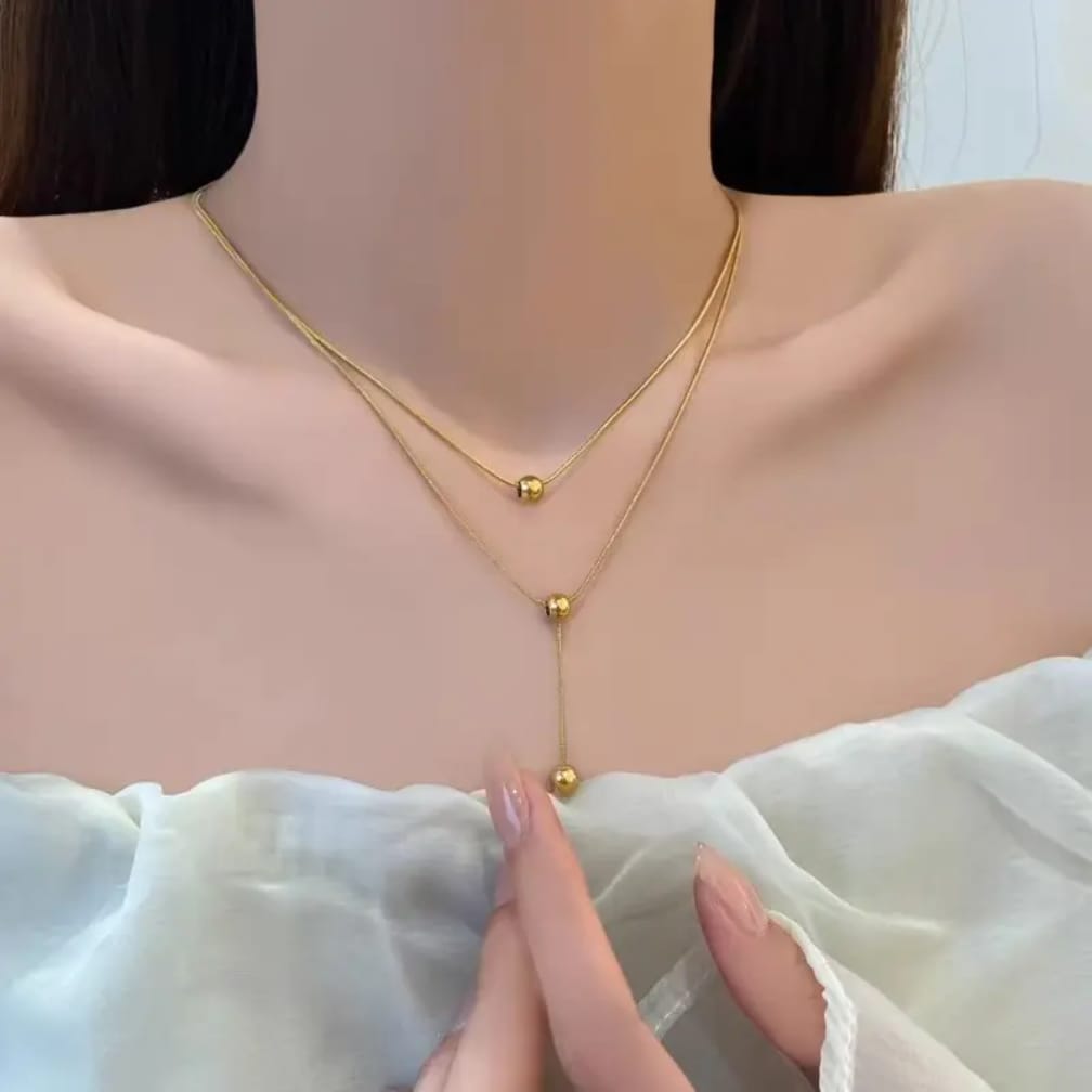 Gold layered Y necklace with ball accents worn on model